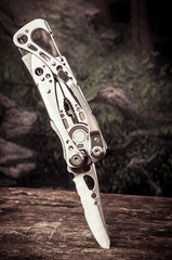multitool, multi purpose tool with knife stuck on wood
