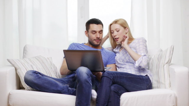 smiling couple with laptop computer at home