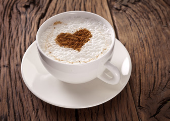 Cup of cappuccino with ground cinnamon in the form of heart.