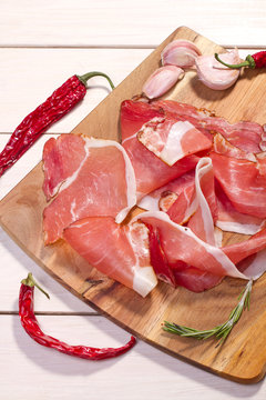 sliced prosciutto on wooden background 