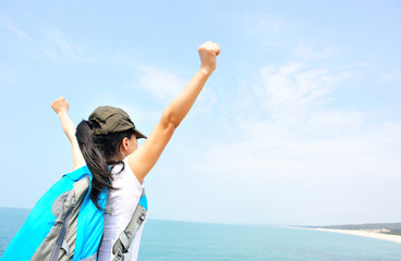 cheering woman hiker open arms at  seaside