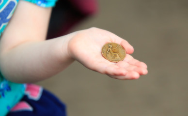 Little hand holding an old penny coin