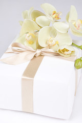 close up of gift box with ribbon and white orchid
