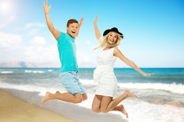 Beautiful smiling young couple jumping  on a beach