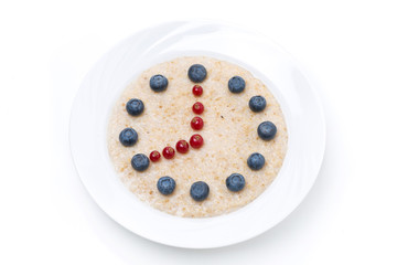 plate of oatmeal with berries in the form of dial, isolated