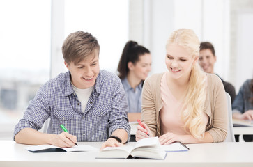 two teenagers with notebooks and book at school