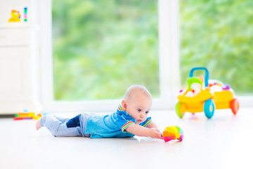 Adorable baby boy playing with a colorful ball and toy car