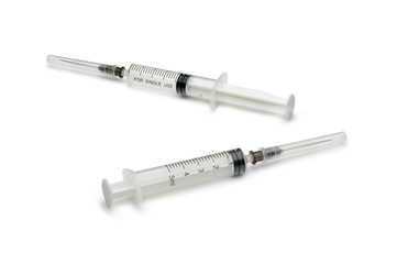Two plastic disposable syringes with a needle in the protective