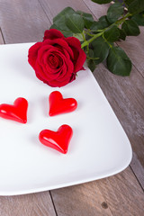 weiße Schale mit roten Herzen und roter Rose