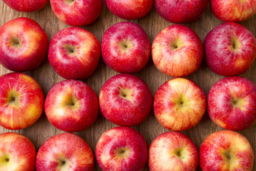 Many red apples with leaves on a wooden background.