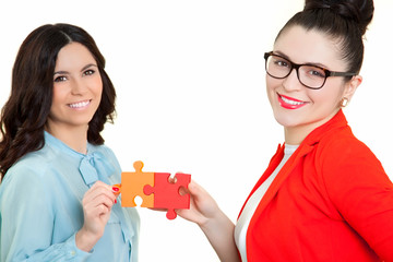 business women assembling jigsaw puzzle and