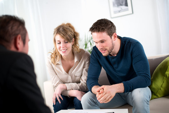 cheerful young couple with salesman at home