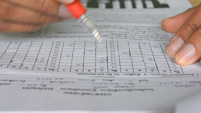 Teacher checking of students exam in scantron sheet