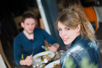 cheerful young couple having lunch outdoor in a restaurant