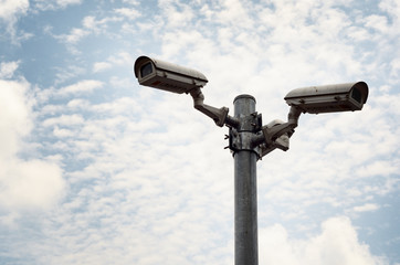Security cameras against blue sky