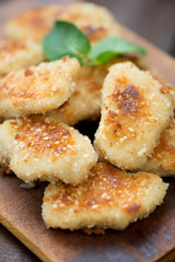 Close-up of fried sesame chicken nuggets with mint, studio shot