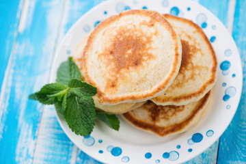 Glass plate with homemade pancakes, blue wooden background
