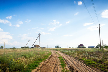 Fototapeta na wymiar Dirt road through the green fields.