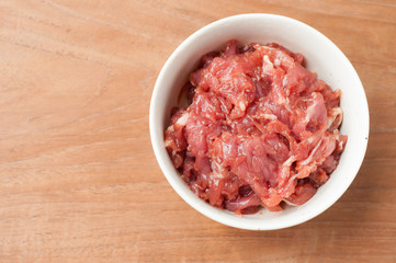 raw beef in white bowl on wooden background