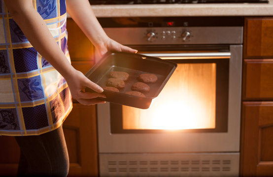 Photo Of Woman Putting Cookies In Oven