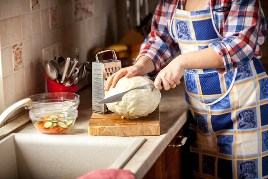 photo of woman cutting cabbage on kitchen
