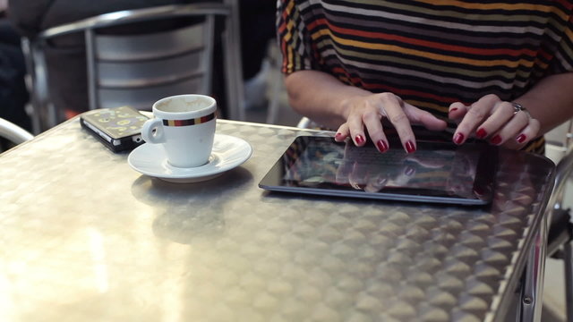 Woman writing e-mail on tablet computer in cafe