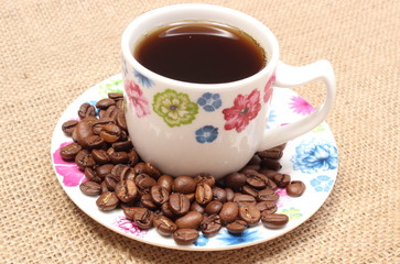 Heap of coffee grains and cup of beverage