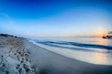 The rising sun peeks through clouds and is reflected in waves by