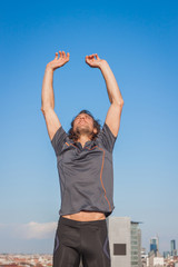Long haired athlete stretching against blue sky