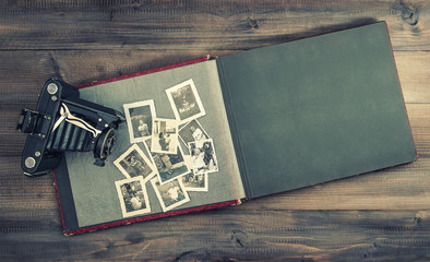 camera and album with old family photos on wooden table