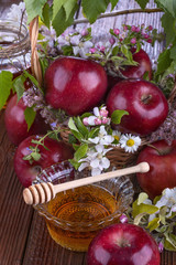 apples in a basket with honey and flowers on wooden table