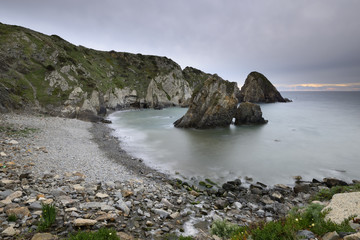 Obraz premium Baía de seixos com pequena ilha de rocha