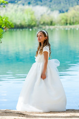 Fototapeta na wymiar Girl in communion dress at lake.