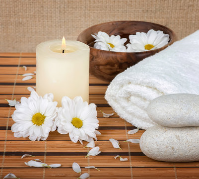 Spa decoration with candle, daisies and spa stones