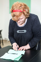 Retirement age woman filling forms at table