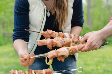 Woman preparing kebabs to grill on a BBQ