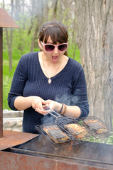 Woman cooking over a BBQ reacting in horror