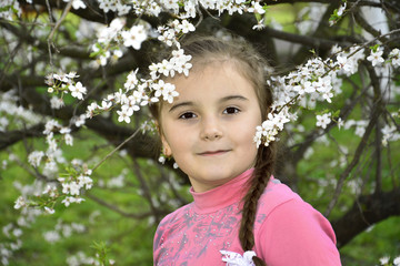 Spring in the garden a little girl holding a cherry branch.