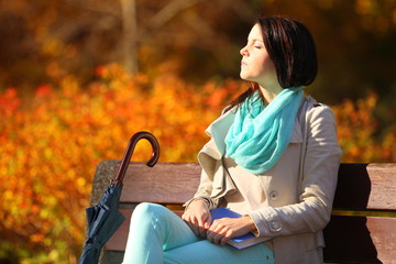 Fototapeta na wymiar Young girl relaxing in autumnal park. Fall lifestyle concept.