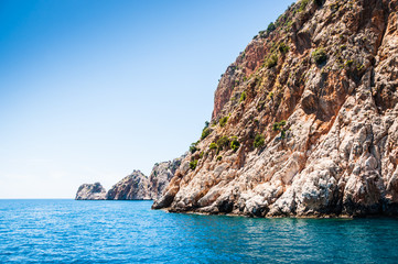 Fototapeta na wymiar Piękne błękitne morze i dzikie skały. Letni krajobraz.