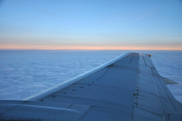 Fototapeta na wymiar airplane wing above morning clouds and sunrise