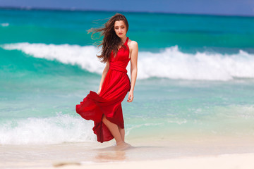 beautiful woman in a red dress  standing on the tropical sea co