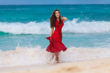 Fototapeta na wymiar beautiful woman in a red dress on the tropical sea coast