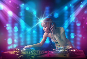 Fototapeta na wymiar Dj girl mixing music in a club with blue and purple lights