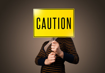 Young woman holding a caution sign