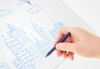 A person drawing sketch of a city with balloons and clouds on a