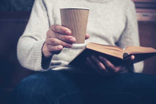 Man reading and drinking from paper cup