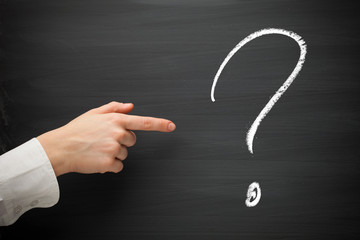 forefinger point at question sign on a blackboard