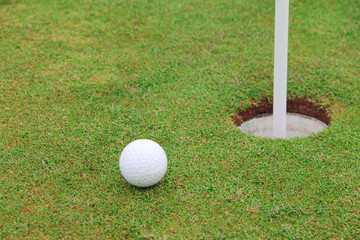 Golf ball on lip of cup