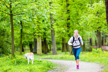 Woman runner walking with dog in summer park